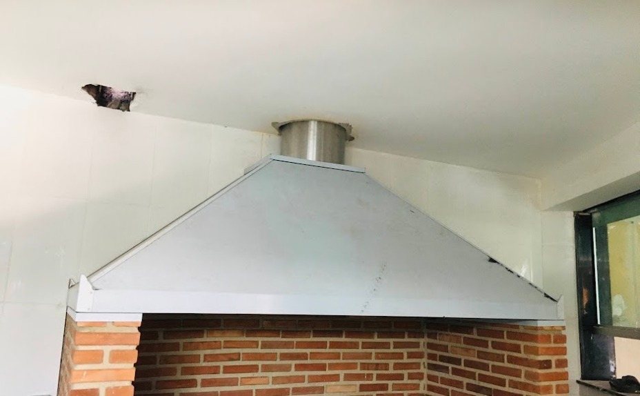 Coifa industrial sob medida em aço inox, instalada sobre churrasqueira de alvenaria